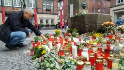 Ein Mann legt Blumen vor der Gaststätte Kiepenkerl in Münster.