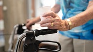 Frau mit Rollator hält Getränkebecher in der Hand