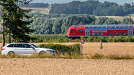 Ein Auto fährt an einem Regionalexpress vorbei