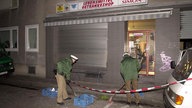 Polizeibeamte kehren nach einen Bombenanschlag am 19.01.2001 auf ein Lebensmittelgeschäft in Kölner Probsteigasse Scherben zusammen