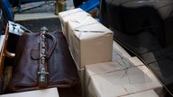 Verschnürte Kartons und eine alte Lederreisetasche auf dem Rücksitz eines Oldtimers