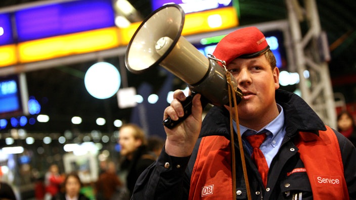 Mitarbeiter der Bahn hält ein Megafon in der Hand