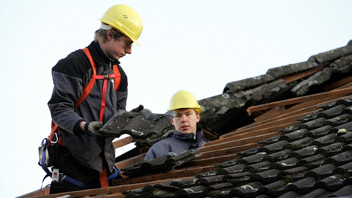 Dachdecker bergen kaputte Ziegel von einem Dach