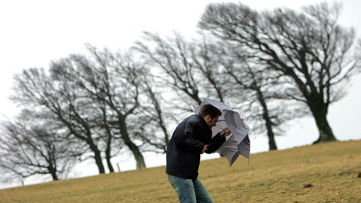 Mann mit Regenschirm im Sturm