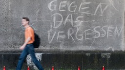 Ein Passant geht am Veranstaltungsgelaende der Loveparade 2010 an dem Schriftzug _Gegen das Vergessen_ vorbei