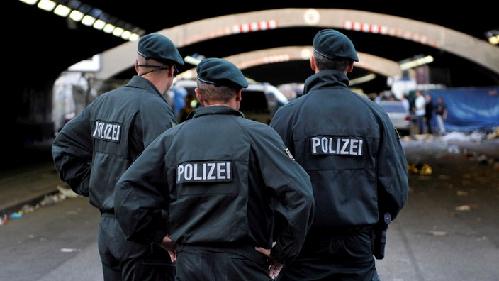 Drei Polizisten stehen vor dem Unglückstunnel der Loveparade