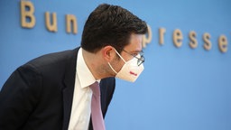 Marco Buschmann von der FDP mit Maske im Seitprofil. Hinter ihm steht "Bundespressekonferenz" an der Wand.