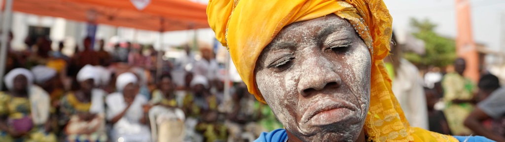 Frau mit Kopftuch und weiß geschminktem Gesicht beim jährlichen Voodoo-Festival in Benin