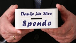 Mann hält Büchse mit Aufschrift Danke für Ihre Spende