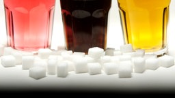 Zuckerwüfel und drei Gläser mit bunten Softdrinks