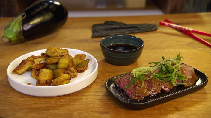 Pochiertes Rinderfilet mit Auberginenwürfeln und Ponzu wird serviert.