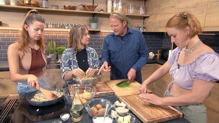 Das Bild zeigt Björn Freitag mit den WG-Bewohnerinnen Daria, Leandra und Joelle beim Kochen.