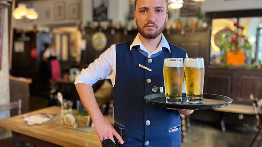 Kellner steht mit Tablett und zwei Bier in Gasthaus