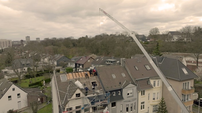 Vogelperspektive eines Hauses, auf dem Handwerker das Dach decken