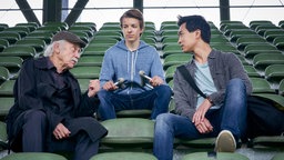 Edwin Bremer (Tilo Prückner, l.) und Hui Ko (Aaron Le, r.) mit dem verletzten Nachwuchs-Fußballer Leon (Nick Julius Schuck, M.).