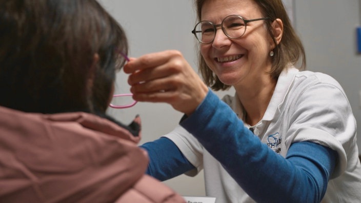 Freundliche Optikerin setzt Brille auf