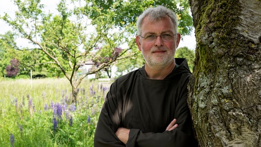 Kapuziner Bruder Bernd lehnt an einem Baum.