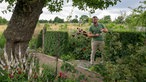 Uli Schauerte in seinem Garten, im Hintergrund Wiesen. 