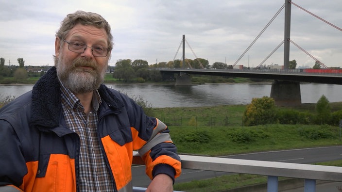 Mann mit Warnweste auf einer Brücke