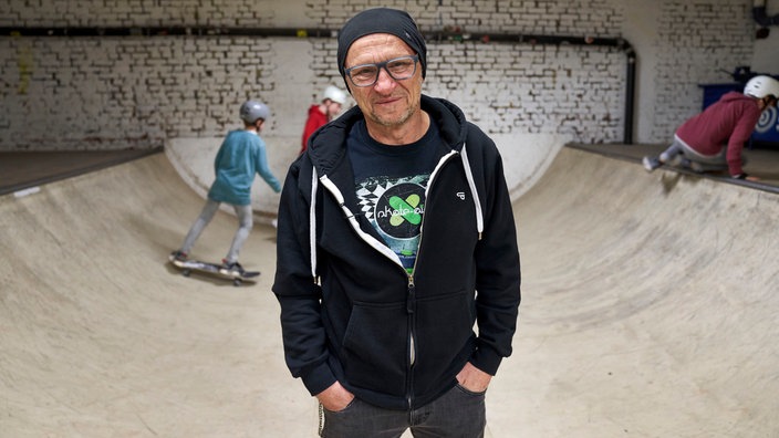 Ein Mann im Hoodie steht vor einer Halfpipe