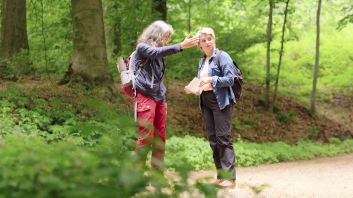 Sabine Heinrich lässt sich im Wald von einer Frau den Weg zeigen