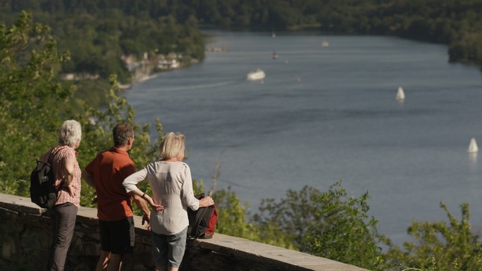 Drei Menschen schauen von aus der Höhe auf den See