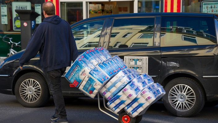 Ein Mann transportiert auf einer Sackkarre Toilettenpapier.