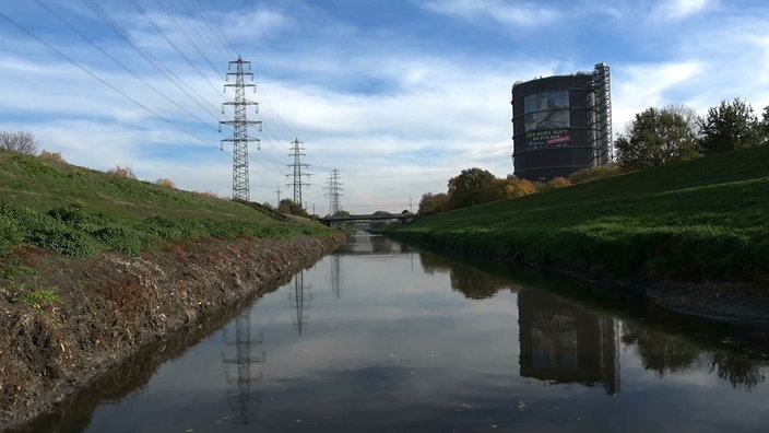 Ein Fluß, links am Ufer Strommasten, rechts der Oberhausener Gasometer