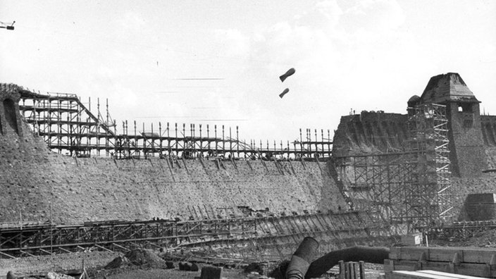 Schwarzweiß-Bild der Möhnetalsperre: eine Baustelle mit Gerüsten 