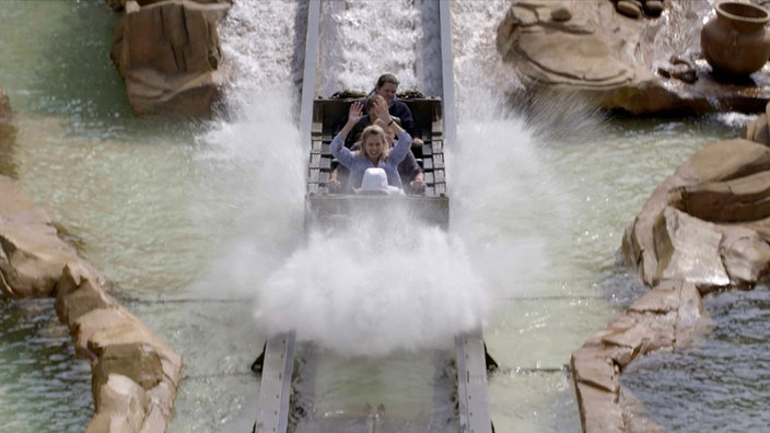 Ein Achterbahnwaggon mit Fahrgästen fährt durch Wasser