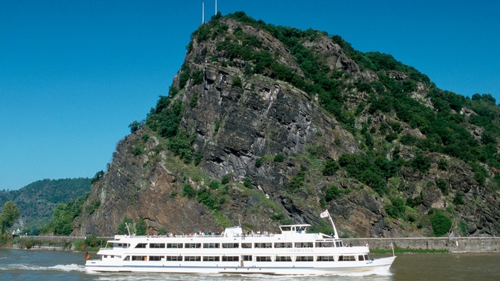 Ein weißes Ausflugsschiff auf dem Rhein vor der Loreley