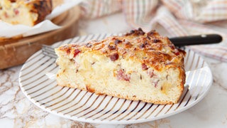 Ein Stück Zwiebelkuchen. Präsentiert auf einem Teller mit Gabel.