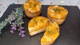 Mini-Käsekuchen auf einer Platte mit Blumen dekoriert