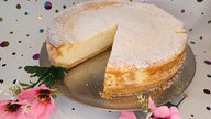 Käsekuchen auf einer Kuchenplatte mit Blumen dekoriert