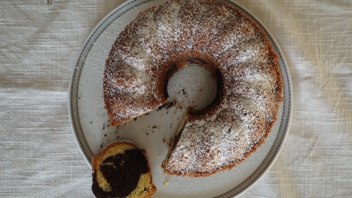 runder angeschnittener Marmorkuchen von oben, ein Stück liegt im Vordergrund