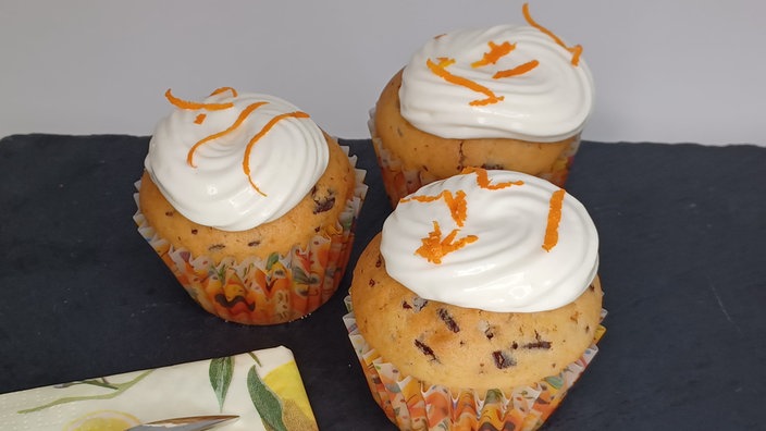 Orangenmuffins mit Frosting und Orangenschalenverzierung