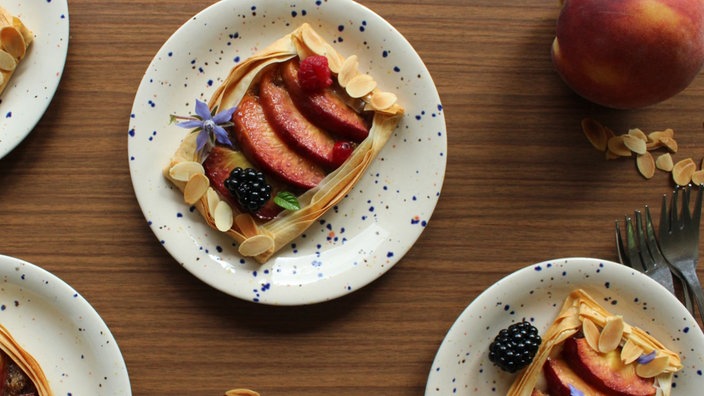 Tartelettes aus Filoteig mit Pfirsich und Nussfüllung auf gepunkteten Tellern