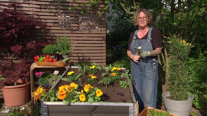 Gartenbloggerin Anja Klein vor dem Hochbeet mit gelben Blüten.