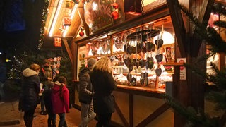 Eine Familie vor einer beleuchteten Bude auf einem Weihnachtsmarkt