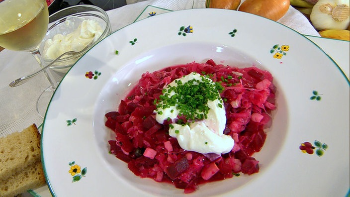 Eintopf mit Kassler, Sauerkraut und Rote Bete mit einem Klecks Yoghurt und Schnittlauch in einem Teller angerichtet