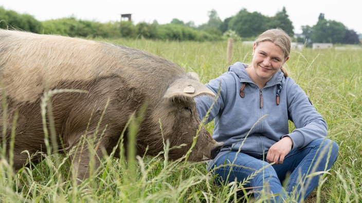 Eva Bird auf der Weide mit einem Schwein. 