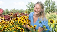 Anna Pröbstle inmitten einer Blumenwiese.