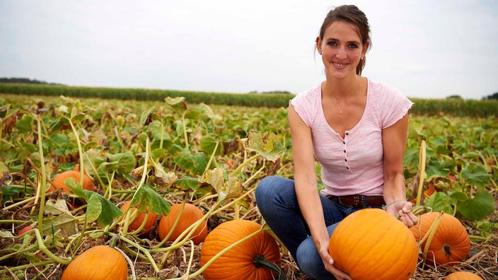 Lea Unterhansberg auf dem Feld mit einem Kürbis. 