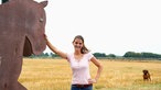 Lea Unterhansberg lehnt an einer Pferdestatue.