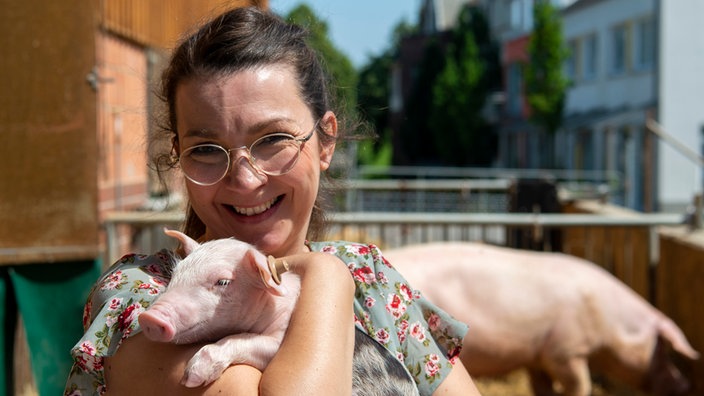 Nicole Nassiry mit einem Ferkel auf dem Arm.