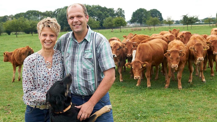 Christiane und Martin Engels schauen mit ihrem Hund nach ihren Kühen.