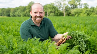 Rainer Overkämping mit einem Bund Möhren in der Hand.