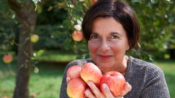 Sylke Lenzen mit den Händen voller Äpfel.