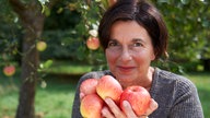 Sylke Lenzen mit den Händen voller Äpfel.