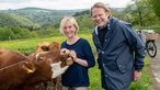 Björn Freitag mit Caroline Fournier auf der Weide mit Rindern. 